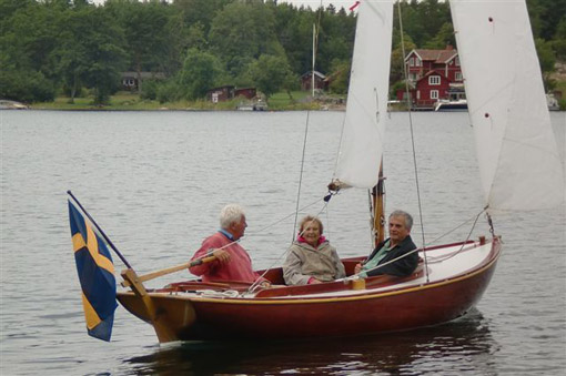 Bild på en Junibåt som seglar med Sonja Herlin och sonen Tore samt, vid rodret, Petter
